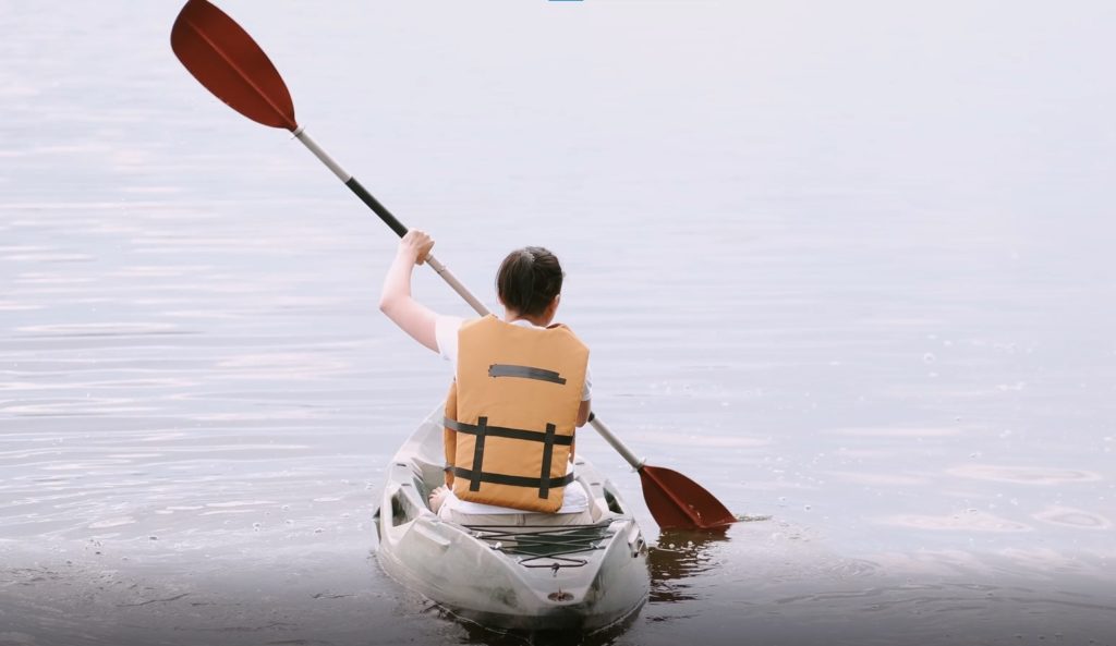 A woman sweeping the paddle to turn the kayak