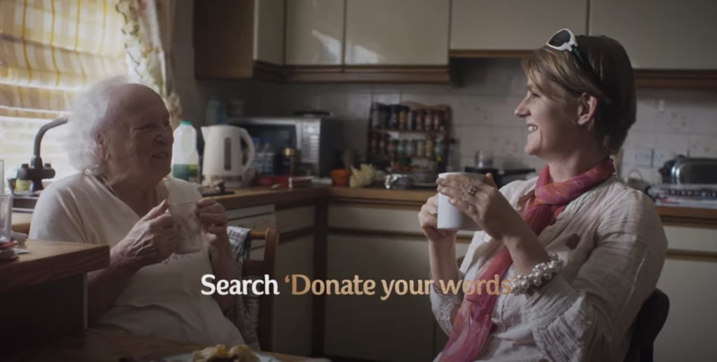 An elderly woman smiling and chatting with an younger female. 